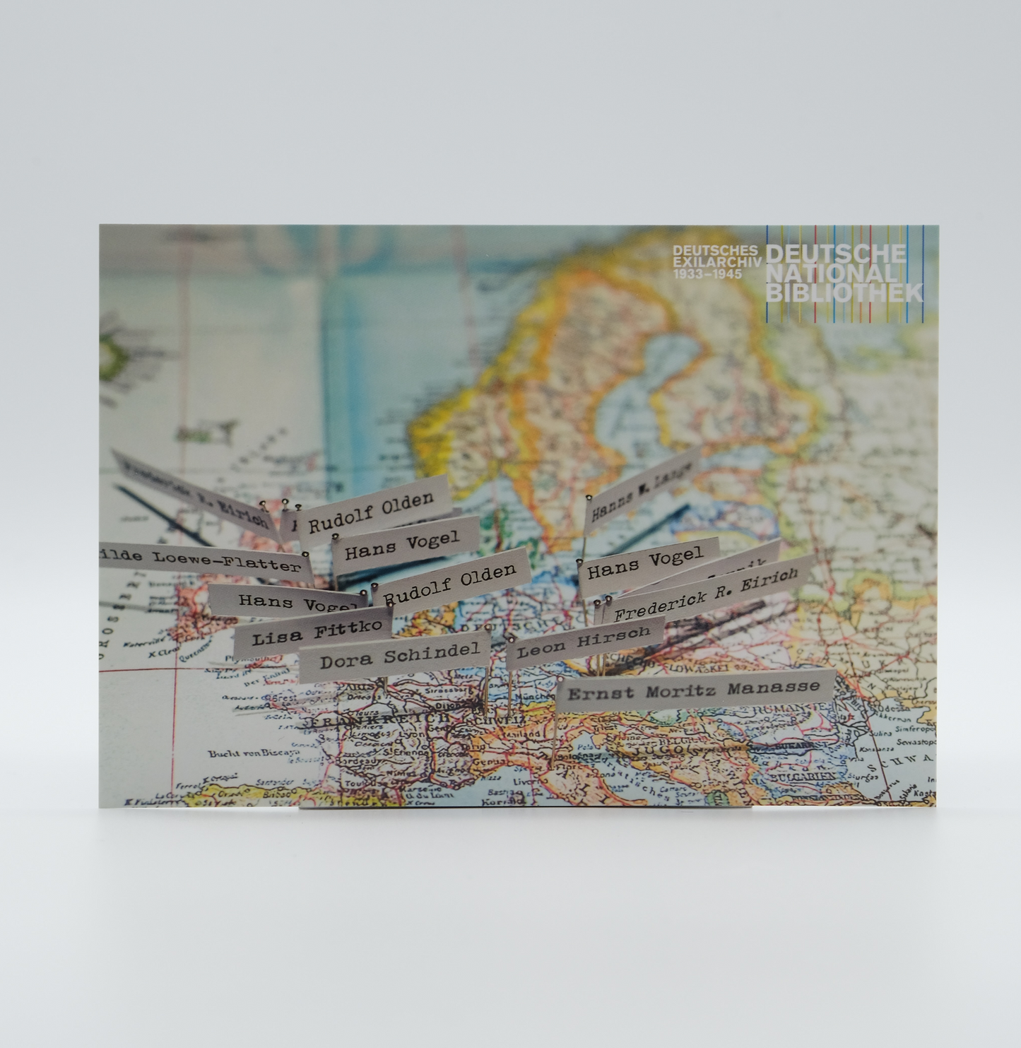 Postkarte zeigt eine Landkarte mit Namensschildern für die Ausstellung "Fremd bin ich den Menschen hier"